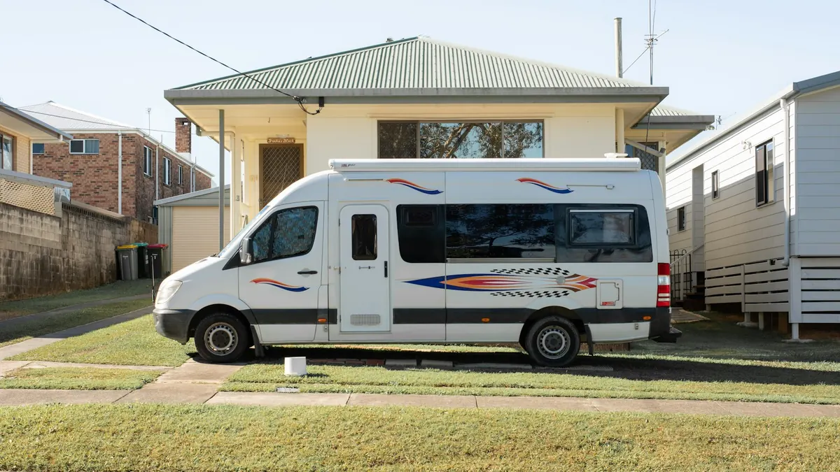 Camping-car stationné devant une maison individuelle, vue latérale